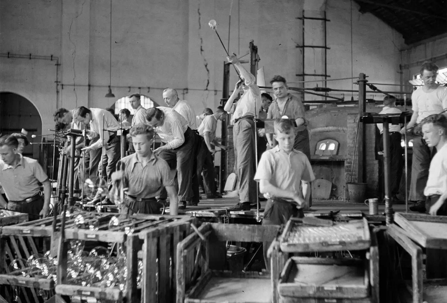 Factory workers blowing glass light bulbs and handling them. Factory workers blowing glass light bulbs and handling them.