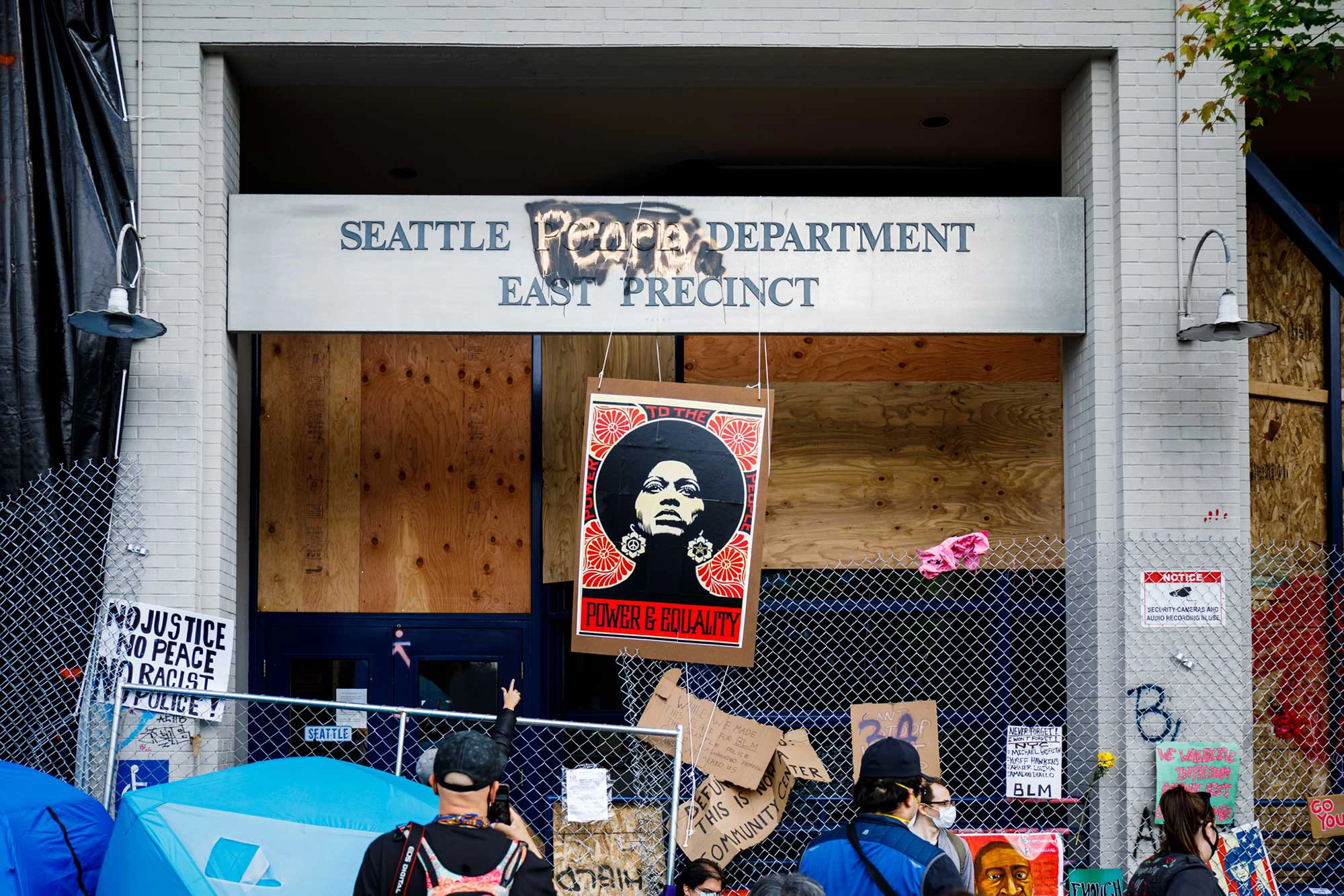 A portrait of Angela Davis hangs in front of an abandoned Seattle Police precinct within the CHAZ. A portrait of Angela Davis hangs in front of an abandoned Seattle Police precinct within the CHAZ.